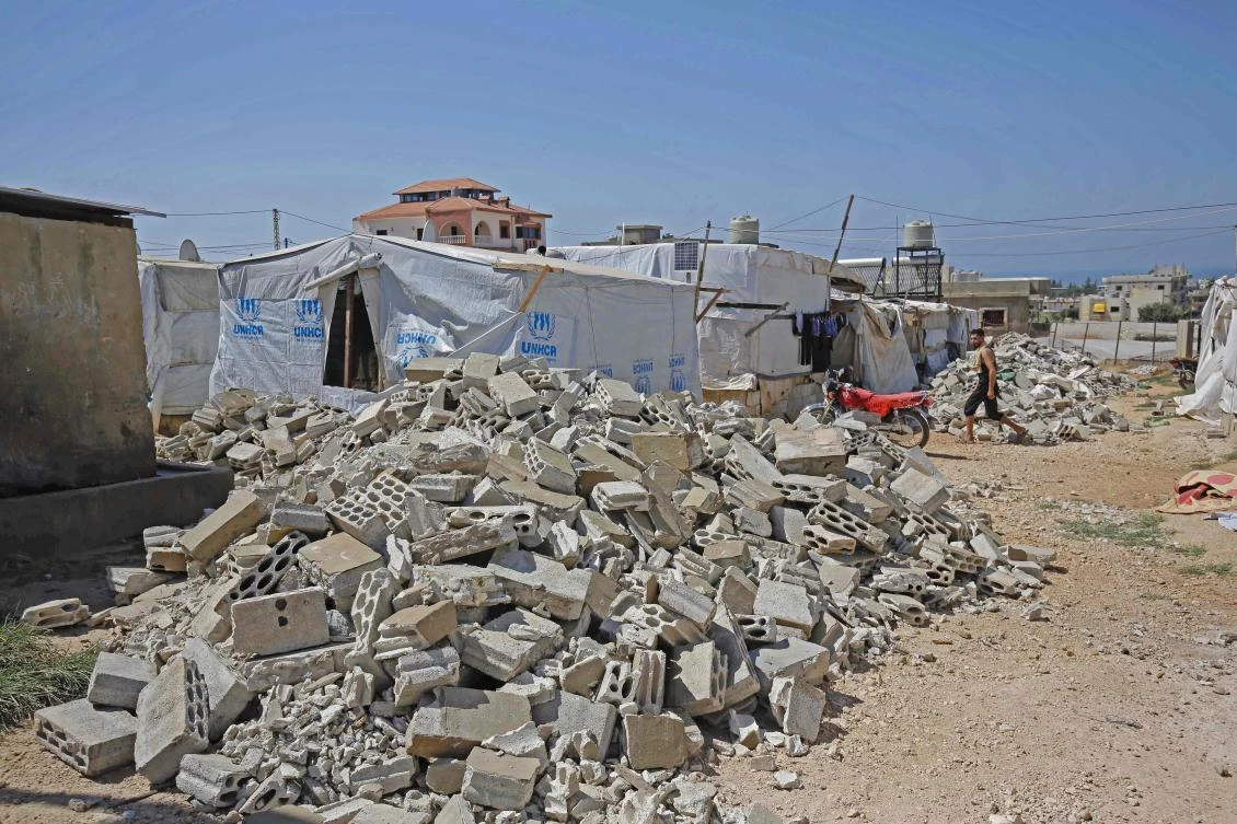 A Syrian refugee walks past the rubble of demolished concrete walls at a make-shift camp in the town of Rihaniyye in Lebanon’s Akkar governorate. (AFP)