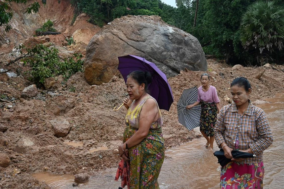 Residents walk past an area affected by a landslide in Mutkyi village in Paung township. A fatal landslide in southeastern Mon state was followed by heavy flooding that reached the roofs of houses and treetops in nearby towns. (AFP)