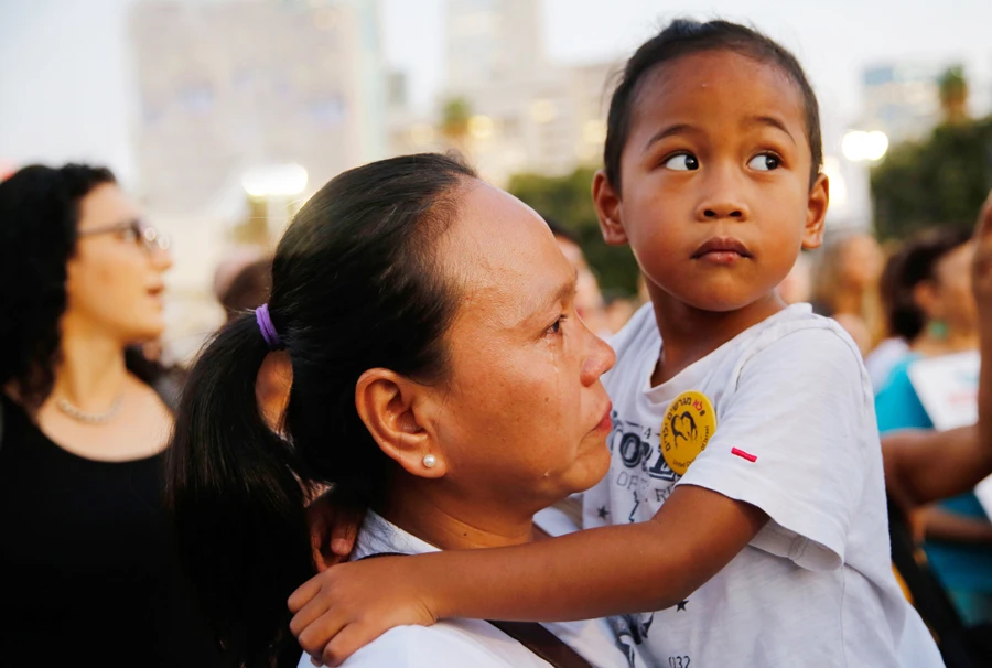 A Philippine migrant mother carries her Israeli-born teenage child, Rohan, during a protest against deportation in Tel Aviv, Israel. (AFP)