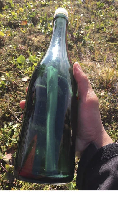 This undated photo provided by Tyler Ivanoff shows a bottle with a message that he found on the shores of western Alaska. Ivanoff found the handwritten Russian letter dated 1969 early this month while gathering firewood near Shishmaref about 966 kilometers northwest of Anchorage, KNOM-AM reported on Aug. 13. (Tyler Ivanoff via AP)