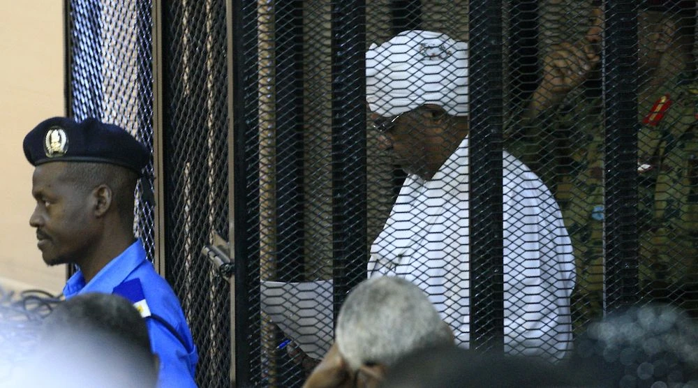 Sudan's deposed military ruler Omar Al-Bashir stands in a defendant's cage during the opening of his corruption trial in Khartoum Monday. (AFP)