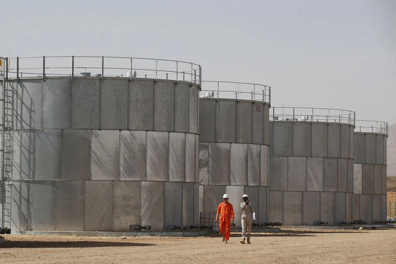 Workers walk past storage tanks at Tullow Oil’s Ngamia 8 drilling site in Lokichar, Kenya. (Reuters)