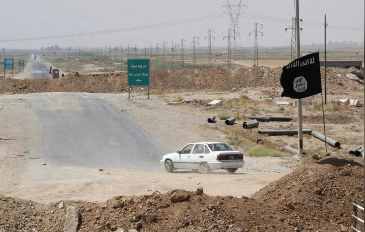 A car drives near a flag belonging to Islamic State militants at the end of a bridge in southern Kirkuk, August 23, 2014. (Reuters)