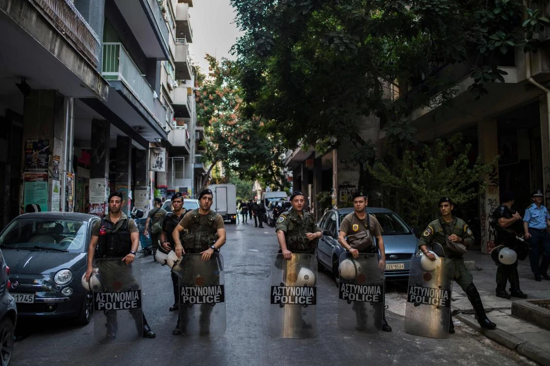 Police officers stand guard outside a building during an evacuation operation, in the Exarchia district, central Athens. (AFP)