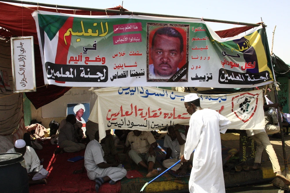 A banner bearing the portrait of Sudanese teacher Ahmed Al-Kheir, who died from wounds suffered in detention during Bashir’s regime, hangs on a tent outside the army headquarters in the capital Khartoum. (File/AFP)