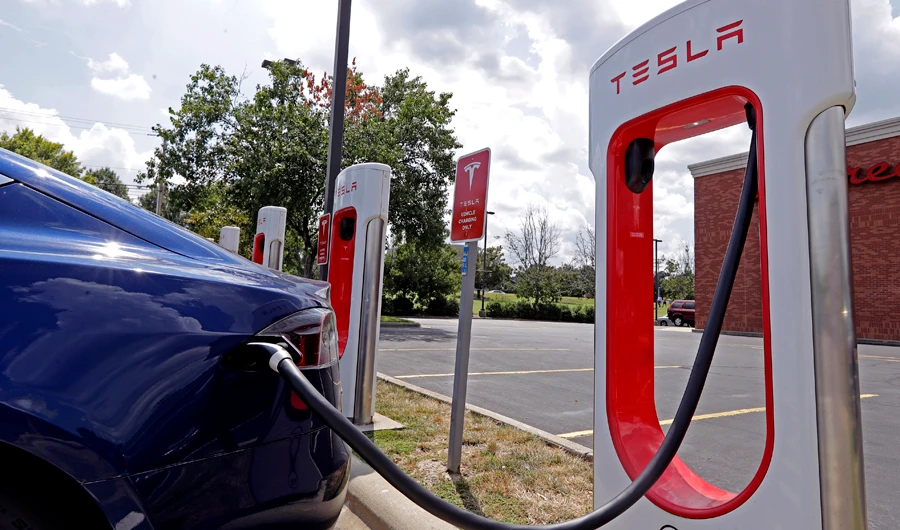 In this file photo, a Tesla vehicle charges at a Tesla Supercharger site in Charlotte, N.C. Tesla owners can now buy insurance policies from the electric car company in what may be an essential step toward it selling driverless vehicles. (AP)