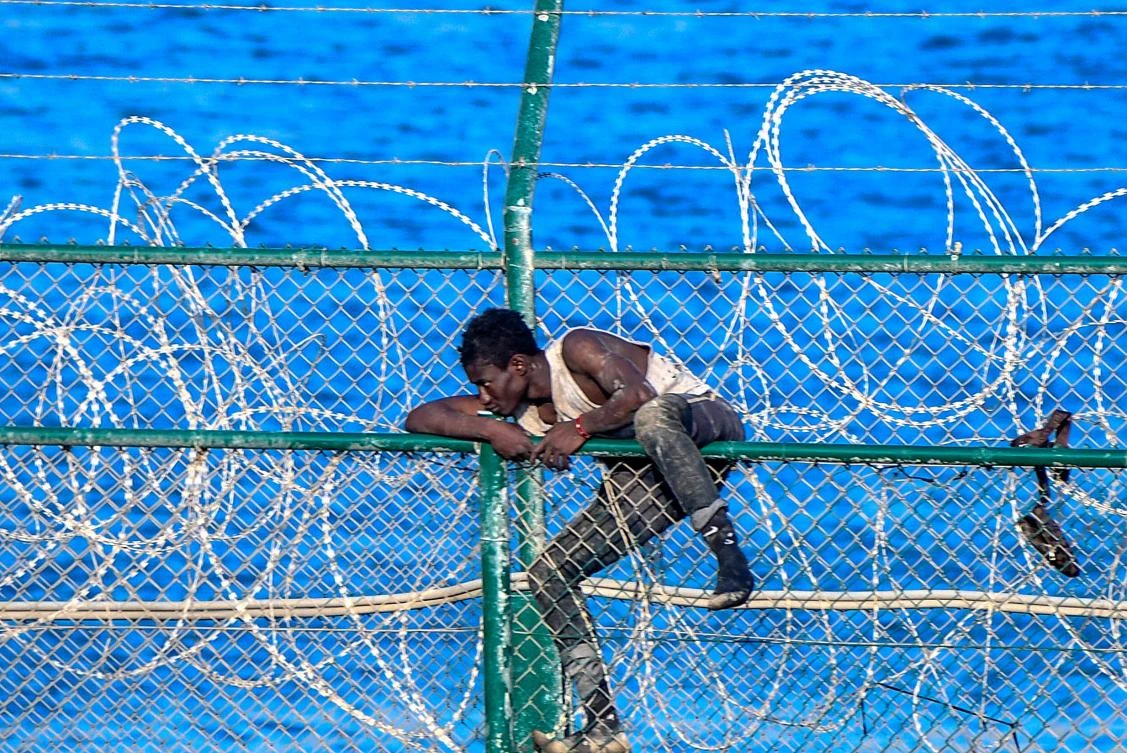 A migrant forces his way into the Spanish territory of Ceuta. Over 150 migrants made their way into Ceuta after storming a barbed-wire border fence with Morocco. (AFP)