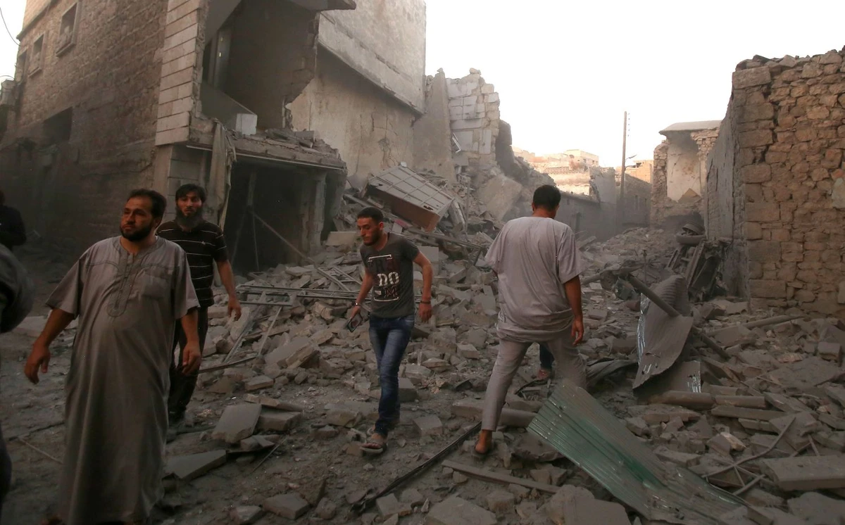 People walk amidst the rubble of damaged buildings following a reported airstrike by Syrian regime forces in the area of Maaret Al-Numan in Syria's northwestern Idlib province on August 28, 2019. (AFP)