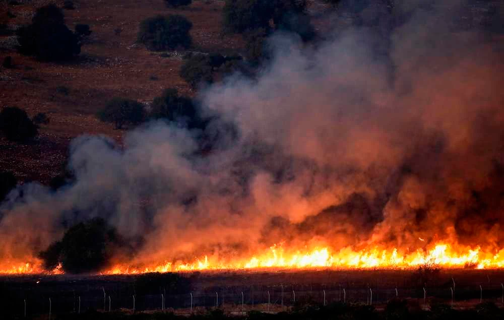 Fire in a field along the border with Israel on the Lebanese side following an exchange of fire. (AFP)