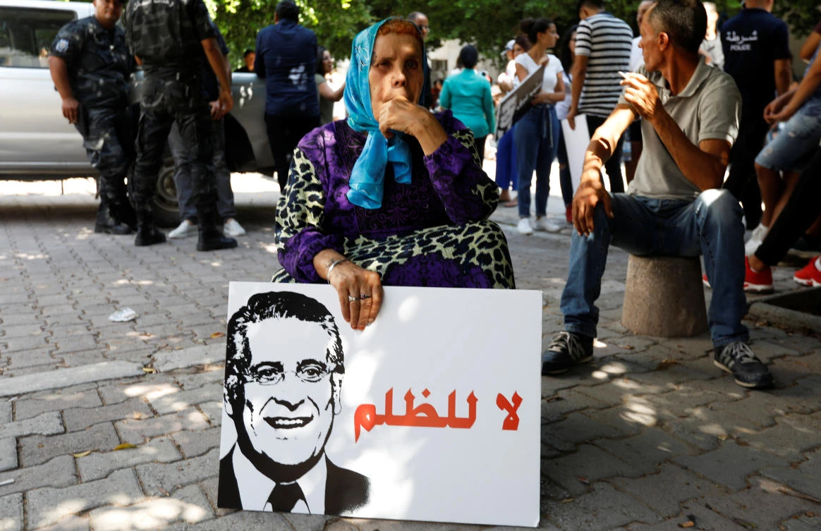 A woman holds a picture of presidential candidate Nabil Karoui during a rally asking for his release from prison, in front of the courthouse in Tunis, Tunisia, September 3, 2019. The placard reads "No to injustice". (Reuters)