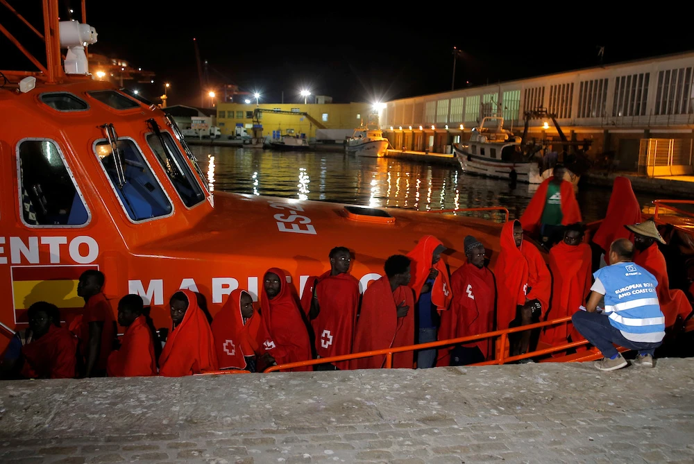A member of Frontex talks to migrants, intercepted off the coast in the Mediterranean Sea, as they wait to disembark from a rescue boat at the port of Malaga, southern Spain. (Reuters)