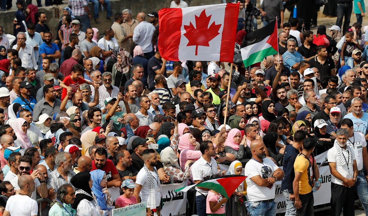 Hundreds of Palestinian refugees waving Palestinian and Canadian flags request asylum at a rally outside the the Canadian Embassy, in Beirut, Lebanon. (AP)