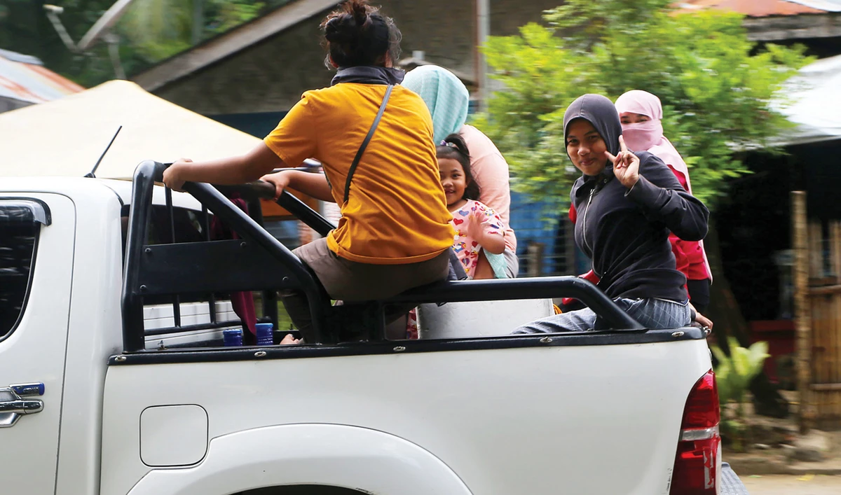 A girl flashes the peace sign while riding a vehicle tailing the convoy transporting MILF firearms to be decommissioned. (AN photo)