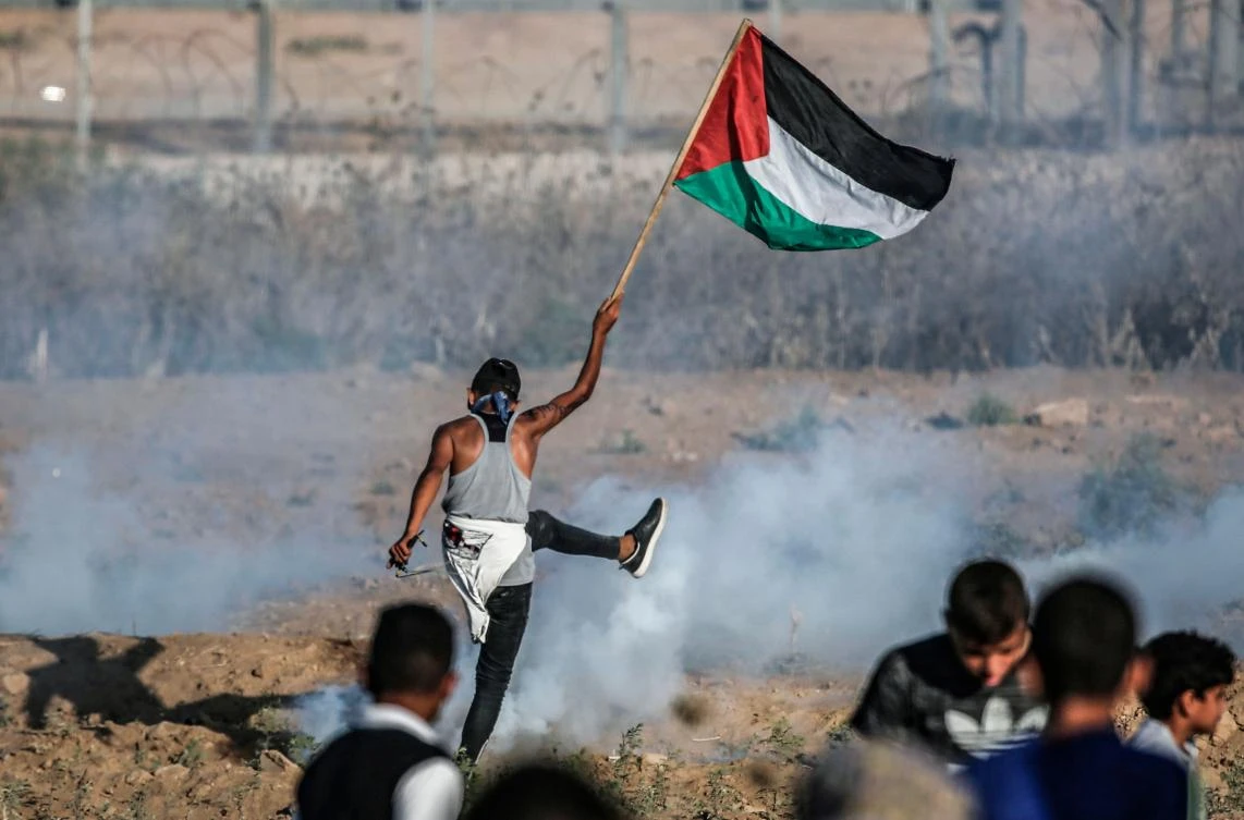 A protester raises a Palestinian flag during clashes with Israeli forces across the border following a demonstration east of Bureij in the central Gaza Strip on September 6, 2019. (AFP)