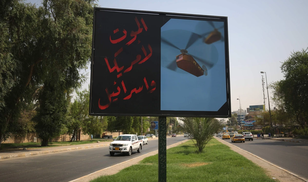 A picture taken on August 30, 2019 shows a billboard, installed by a militant faction belonging to Iraq's Hashed Al-Shaabi (Popular Mobilisation Forces) on a main road in Baghdad bearing the slogan: "Death to America and Israel" next to a picture of a helicopter carrying a coffin draped with the US flag. (AFP)