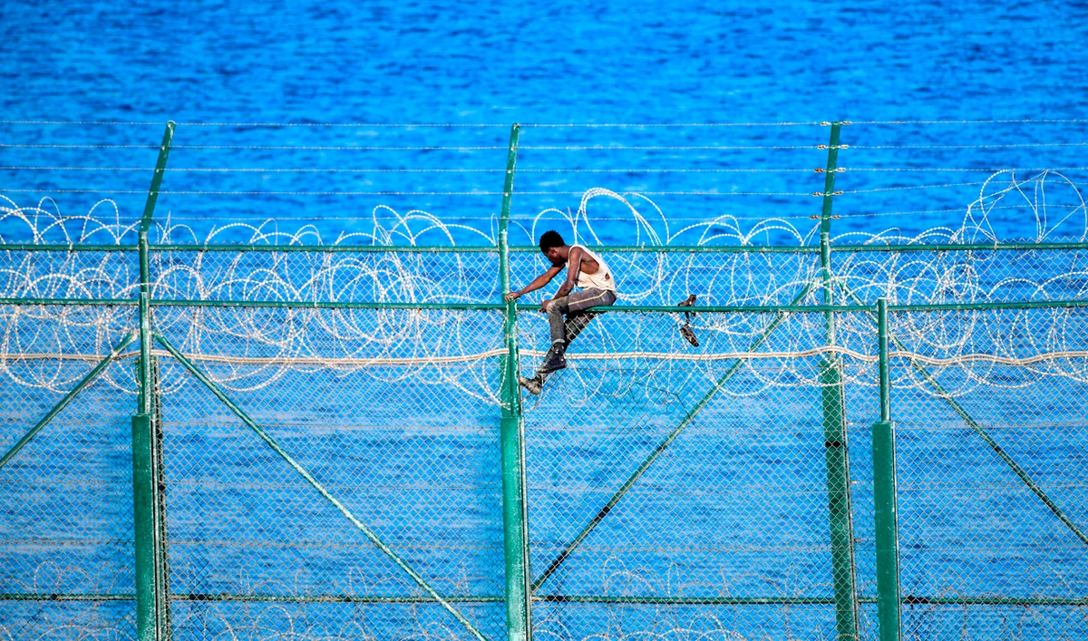 A migrant forces his way into the Spanish territory of Ceuta on August 30, 2019 . Over 150 migrants made their way into Ceuta after storming a barbed-wire border fence with Morocco. (AFP)