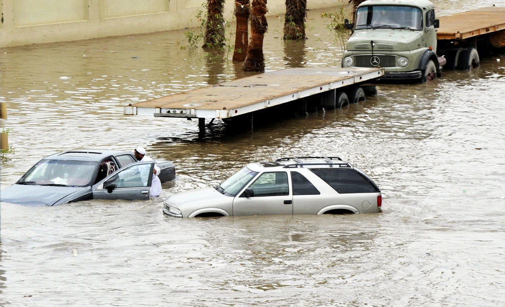 Saudis leave their vehicles in a flooded street following heavy rain in the Red Sea port city of Jeddah on December 30, 2010. (AFP file photo)