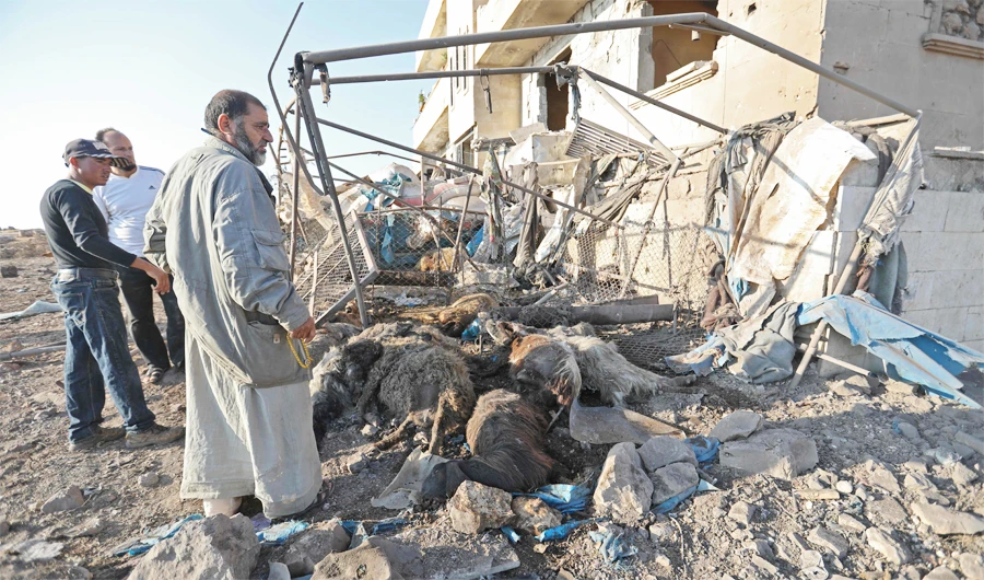 Syrian men look at a destroyed sheep pen following a Russian airstrike in the village of Al-Daher in Syria's northwestern Idlib province on Wednesday. (AFP)