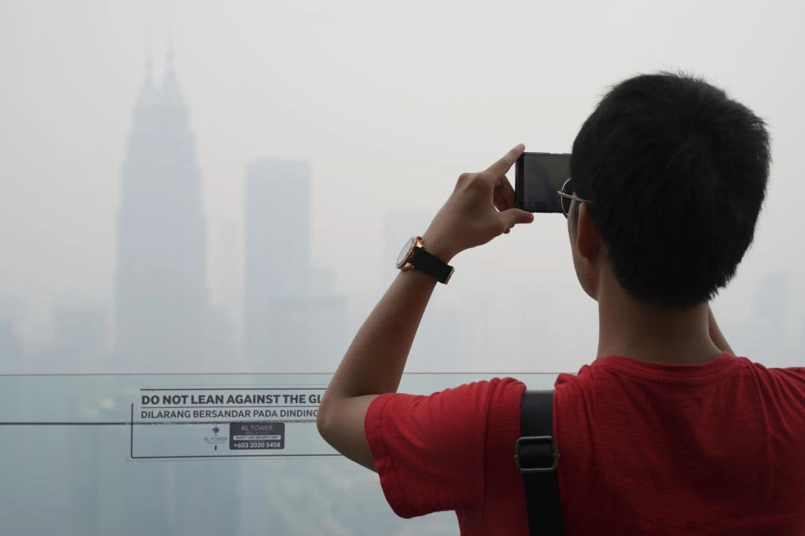 A tourist takes a picture from Kuala Lumpur Tower as the city stands shrouded with haze on Friday, September 13, 2019. (AP)