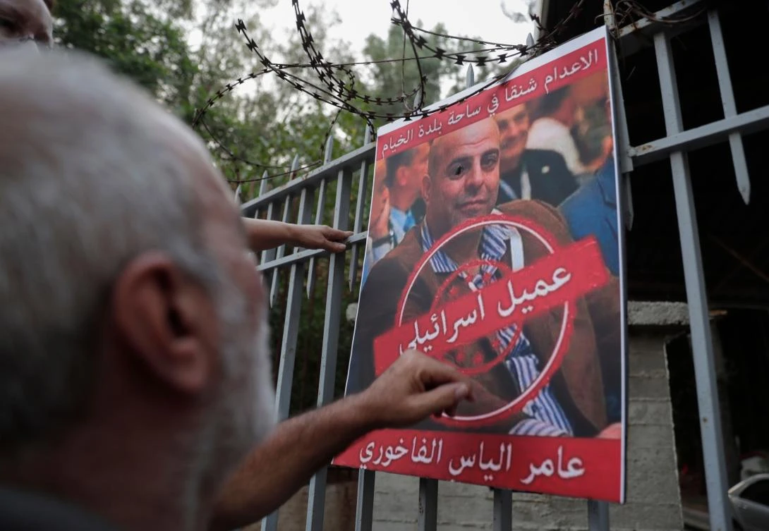 A man formerly detained by the pro-Israel South Lebanon Army (SLA) militia reacts towards a poster depicting former SLA member Amer Fakhoury, during a demonstration denouncing his return and entry outside the Justice Palace in the Lebanese capital Beirut on September 12, 2019. (AFP)