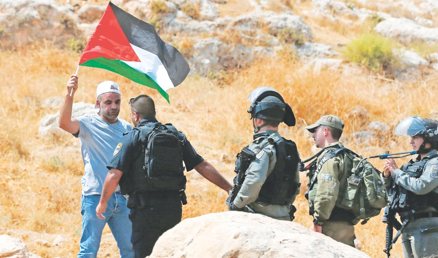 A Palestinian waving his national flag confronts Israeli security forces during a rally against the expropriation of his land by Israel, in Ramallah, on Friday. (AFP)