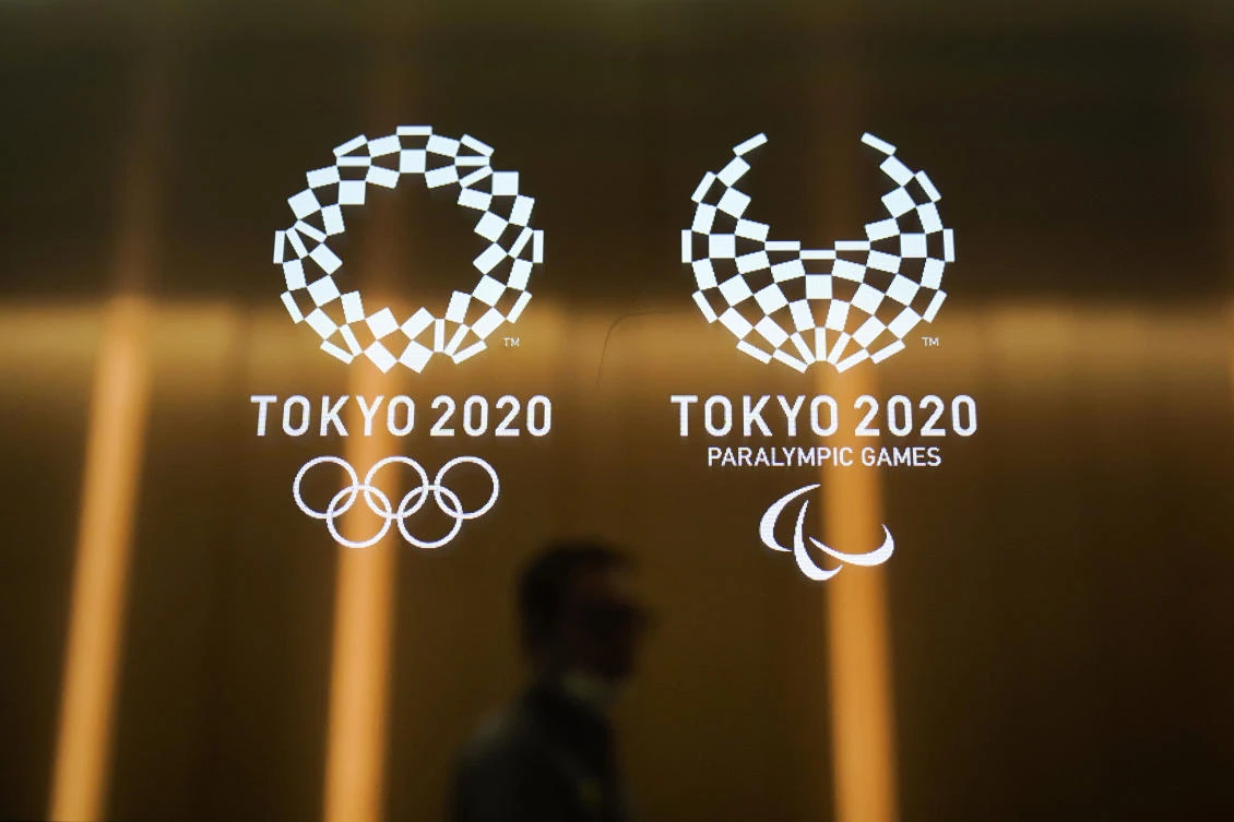 In this June 11, 2019, file photo, a man walks past the logos of the Tokyo 2020 Olympics and Paralympics in Tokyo. (AP)