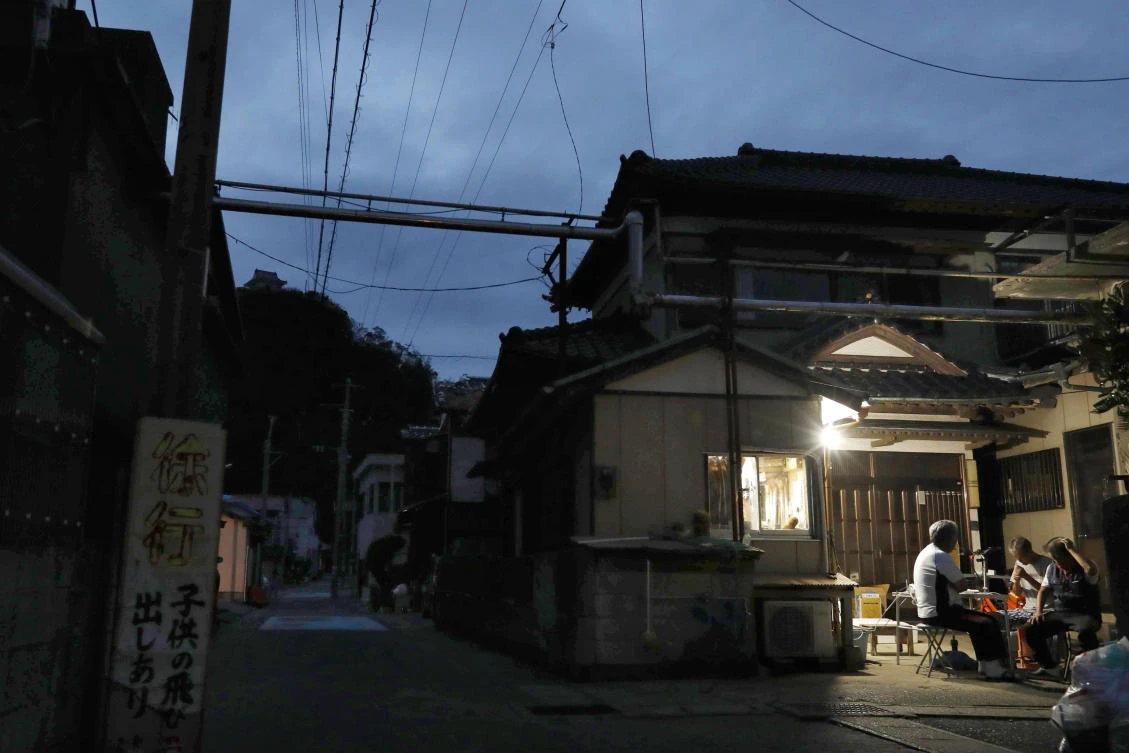 Residents gather near lights from a generator as the struggle to recover power systems damaged by Typhoon Faxai continued in Chiba prefecture, south of Tokyo. (Shinji Kita/Kyodo News via AP)