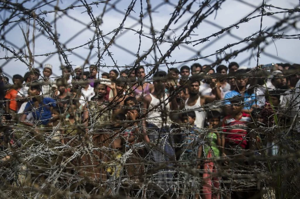 Rohingya refugees gather behind a barbed-wire fence in a temporary settlement setup in a ‘no man’s land’ border zone between Myanmar and Bangladesh on April 25, 2018. (AFP file photo)