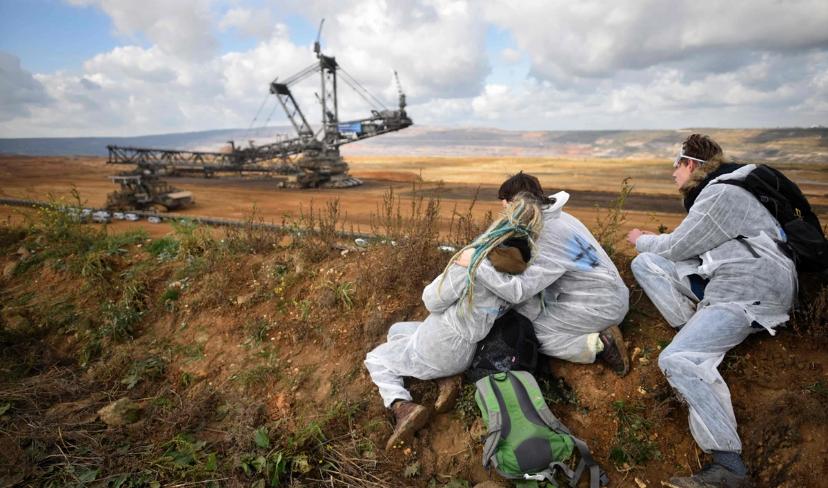 Activists look on as policemen prevent other environmentalists to march further after they managed to enter the Hambach lignite open pit mine near Elsdorf, western Germany, during a protest of environmentalists against fossil-based energies. (AFP)