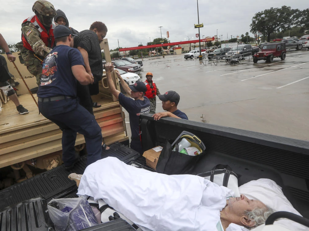 Dwain Kaufman, right, waits for his wife as she is helped into the back of a family member's truck by Beaumont firefighters and members of the Texas National Guard on Sept. 19, 2019, in Beaumont, Texas. (Jon Shapley/Houston Chronicle via AP)