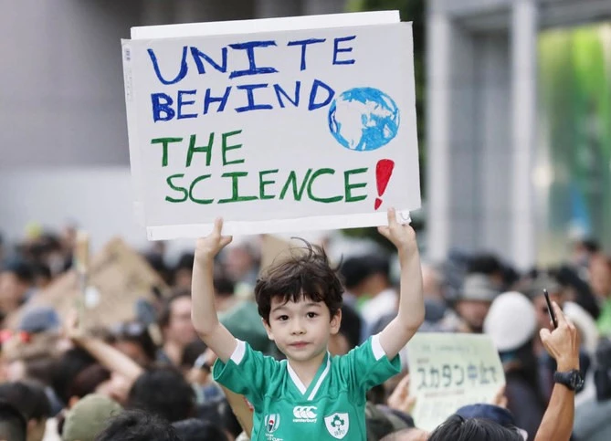 A boy holds up a placard during a rally calling for action to guard against climate change in Tokyo. (Kyodo News via AP)