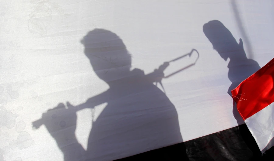 In this Thursday, April 16, 2015 photo, The shadow of Shiite rebels, known as Houthis, are cast on a representation of the Yemeni flag as they attend a demonstration against an arms embargo imposed by the U.N. Security Council on Houthi leaders, in Sanaa, Yemen. (AP)