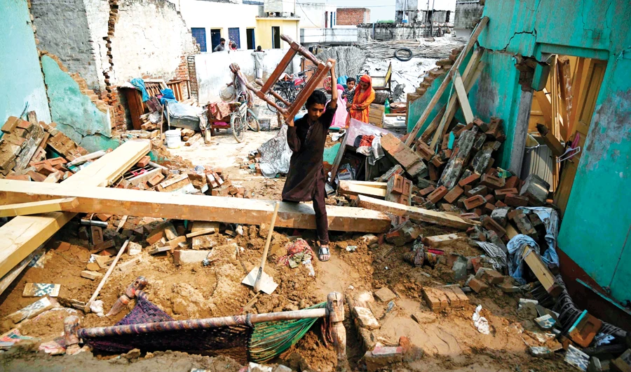 An earthquake survivor moves his belongings in the rubble of collapsed houses on the outskirts of Mirpur in Pakistan-administered Kashmir on Wednesday. (AFP)