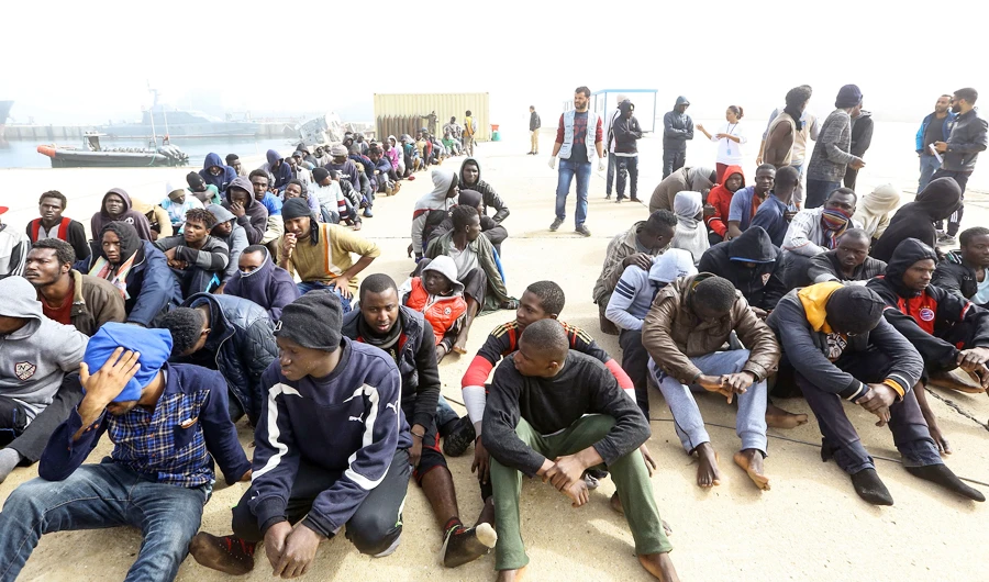 African migrants rescued from a ship off the coast of Zawiyah, about 45 kilometres west of the Libyan capital Tripoli, sit at the dock at the capital's naval base on March 10, 2018. (AFP)
