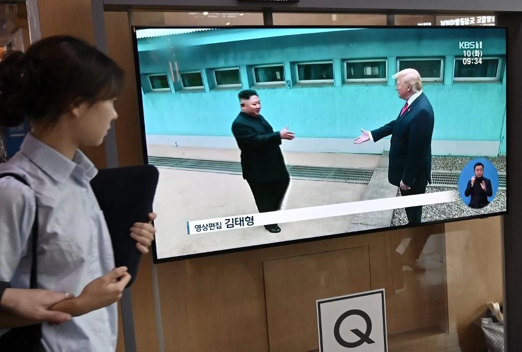 A resident watches a television file footage of US President Donald Trump and North Korean leader Kim Jong Un meeting at the truce village of Panmunjom on June 30, 2019. (AFP)