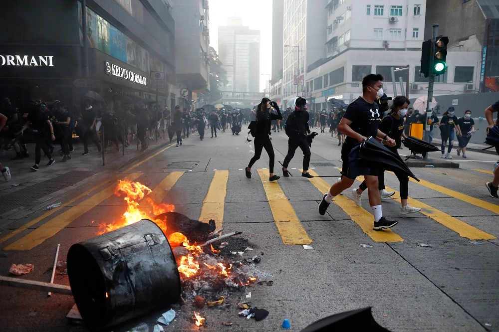 Anti-government protesters set fire to block traffic and run as police arrive in Hong Kong on Tuesday, Oct. 1, 2019. (AP)