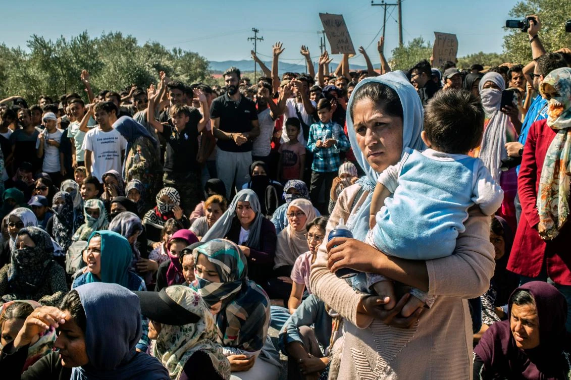 A woman holds a baby as refugees and migrants take part in a demonstration against their living conditions at the Moria camp on the island of Lesbos, on October 1, 2019. (AFP)