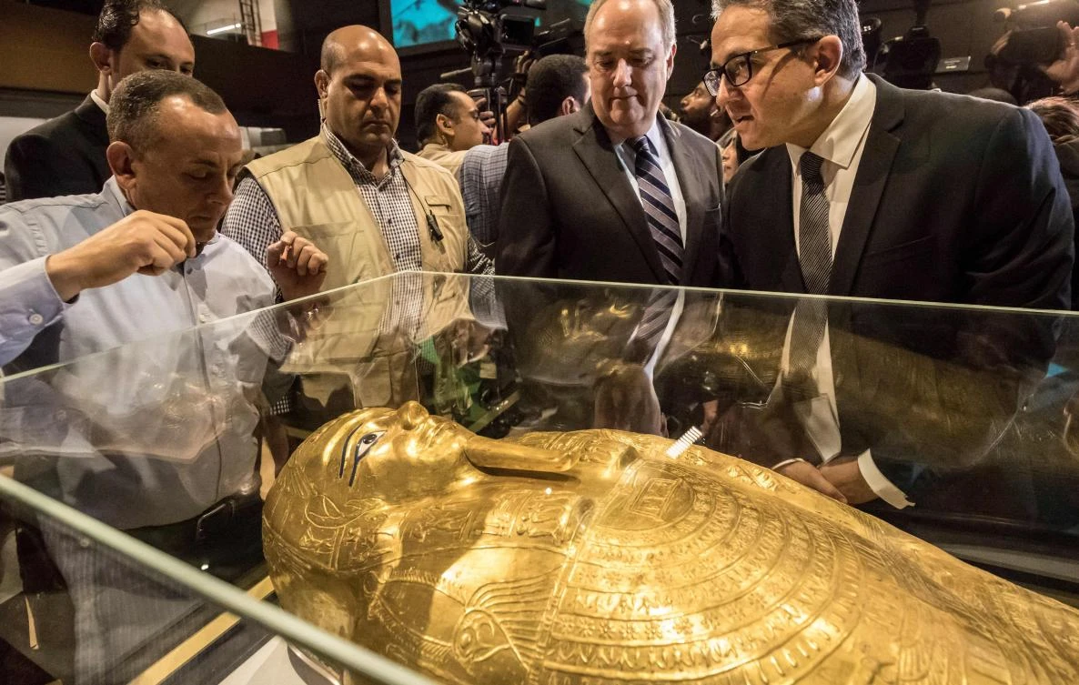 Egypt's Antiquities Minister Khaled El-Enany (R) and Chargé d'Affaires at the U.S. Embassy in Cairo Thomas Goldberger (C) look at the Golden Coffin of Nedjemankh, on display at the National Museum of Egyptian Civilization in Cairo on October 1, 2019, following its repatriation from the US. (AFP)