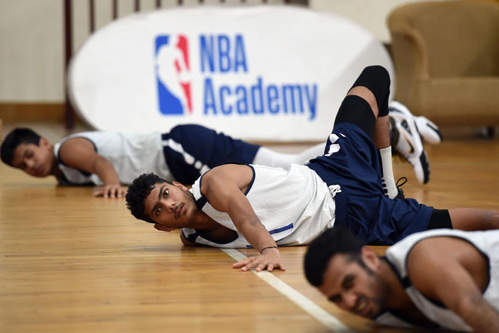 This photo taken on September 13, 2019 shows trainee basketball players stretching during a practice session at the National Basketball Association (NBA) Academy India at Jaypee Sports City in Greater Noida, on the outskirts of New Delhi in Uttar Pradesh state.(AFP / Prakash Singh)