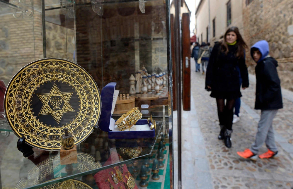 In this file photo taken on February 27, 2014 people stand near a gift shop in the old Jewish Quarters of Toledo. They descend from the Jews expelled from Spain in 1492, and five centuries later, they want to return to their ancestral homeland. (AFP / GERARD JULIEN)