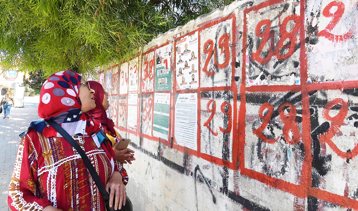 Tunisian women look at posters of legislatives' candidates in the capital Tunis, on October 4, 2019. (AFP)