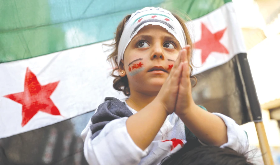 A Syrian girl claps as she takes part in a protest against the regime in the town of Kafr Takharim in Idlib governorate. (AFP)