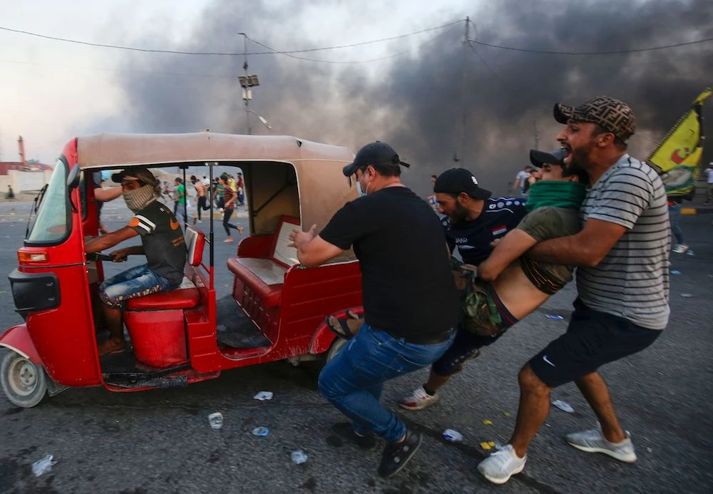 Iraqi protesters evacuate a wounded comrade during clashes in Baghdad Saturday. (AFP)