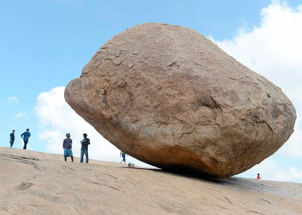 Visitors stand beside the granite boulder 'Krishna's Butterball' at Mahabalipuram. (AFP/File)