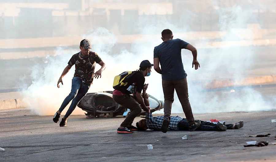 Protesters rush to an injured protester during a rally in Baghdad. (AP)