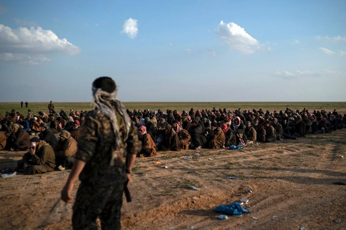 A member of the US-backed SDF stands guard next to men waiting to be screened after being evacuated out of the last territory held by Daesh near Baghouz, eastern Syria. (AP Photo)