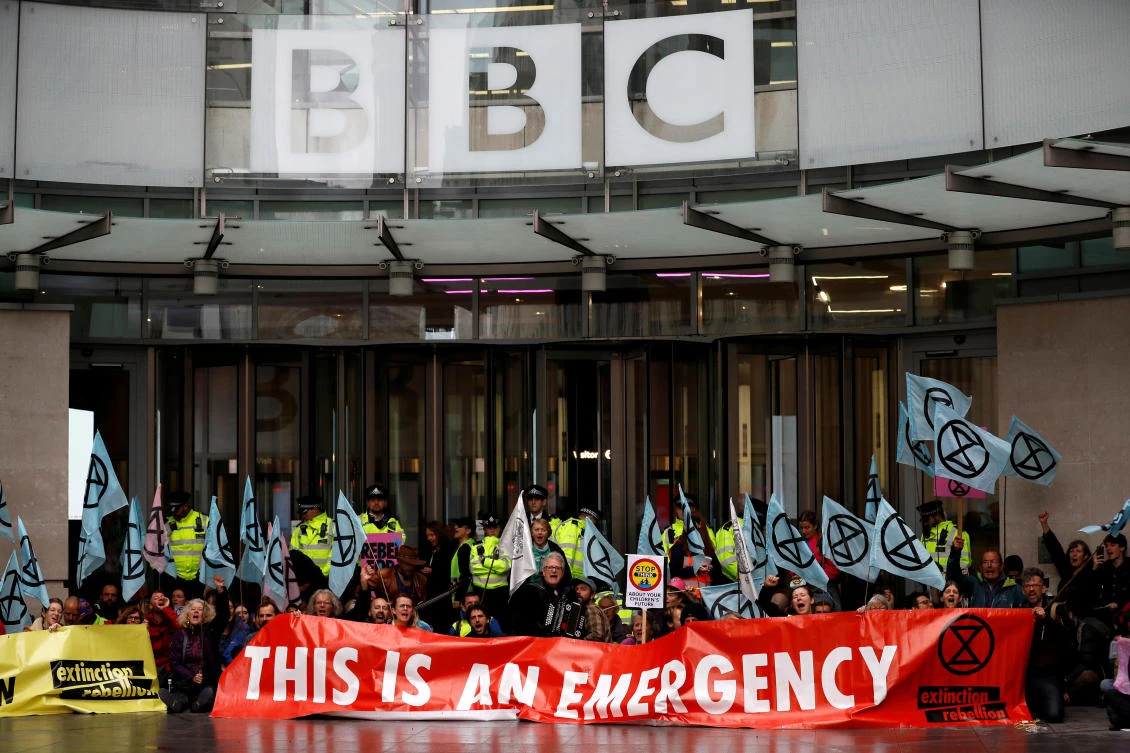 Many of the demonstrators sat in front of the BBC headquarters building in London, holding banners and flags. (Reuters)