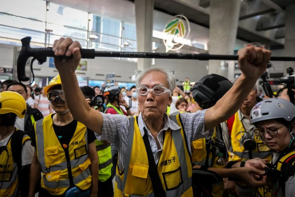 Above, “Grandpa Wong” (C), 85, is shielding protesters from the police by holding his walking stick up along with other “silver hair” volunteers in Hong Kong. (File/AFP)