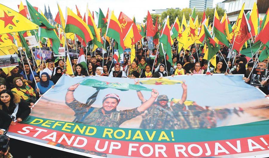 Kurdish protesters hold banner and flags at a rally against Turkey’s military action in northeastern Syria, in Cologne, Germany, on Saturday. (Reuters)