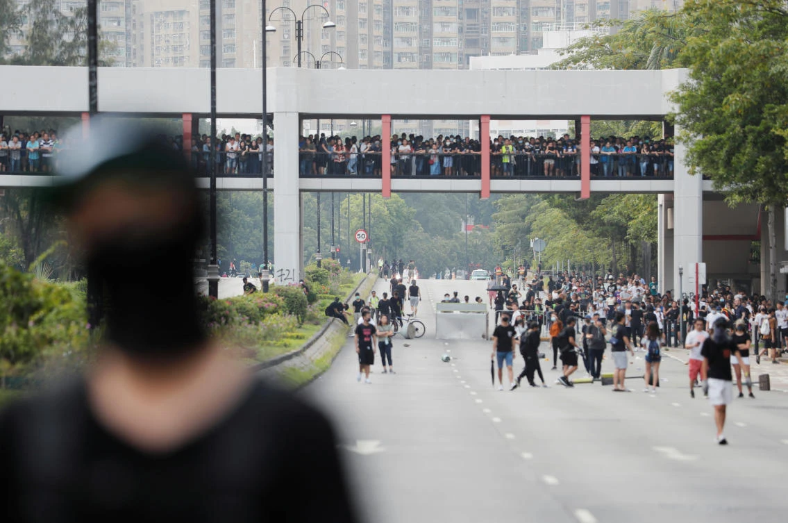 Anti-government protesters walk on the street while people watch from a bridge during a protest in Tai Po district of Hong Kong on Sunday, October 13, 2019. (Reuters)